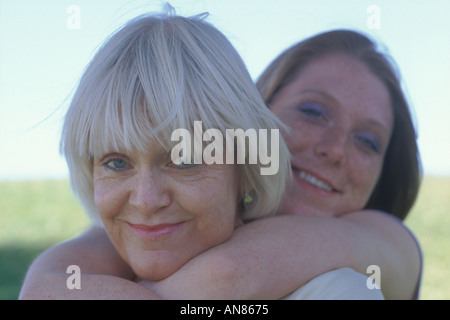 Portrait of 57 year old Caucasian woman and 22 year old daughter hugging her mother from behind Stock Photo
