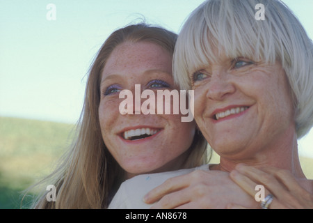 Portrait of 57 year old Caucasian woman with 22 year old daughter hugging her mother from behind Stock Photo