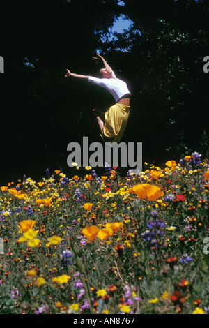 23 year old half Caucasian half African American female jumping in wildflower field Stock Photo