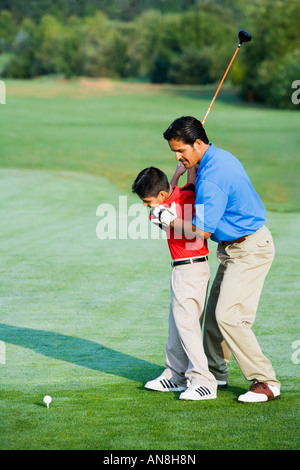 Hispanic father helping son play golf Stock Photo