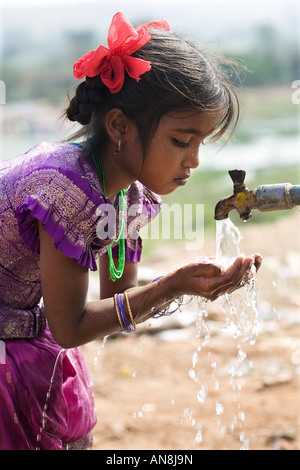 Indian girl drinking from communal water tap. Puttaparthi, Andhra Pradesh, India Stock Photo