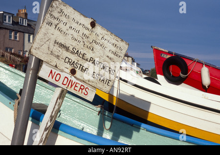 Sign at Craster Harbour, Northumberland, in front of boats on a sunny day Stock Photo