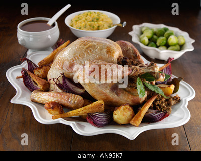 Roast turkey on a white serving platter with stuffing and roasted vegetables Stock Photo