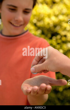 Boy receiving coin in hand Stock Photo