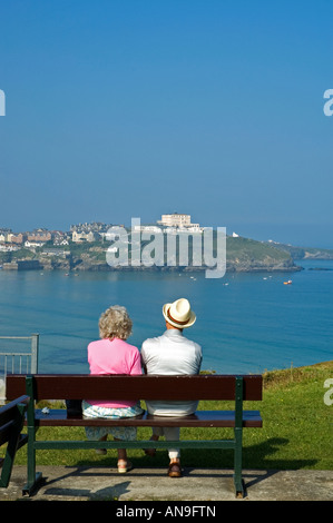 elderly couple sitting on a bench overlooking the bay at newquay,cornwall,uk Stock Photo