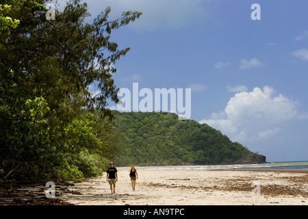 Couple walk on Myall Beach by Cape Tribulation named by Captain Cook Queensland Australia Stock Photo