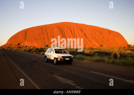 Car drives past Ayers Rock Uluru Red Centre Australia Stock Photo