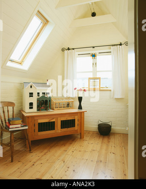 Doll's house on wooden chest in white attic conversion with Velux window Stock Photo