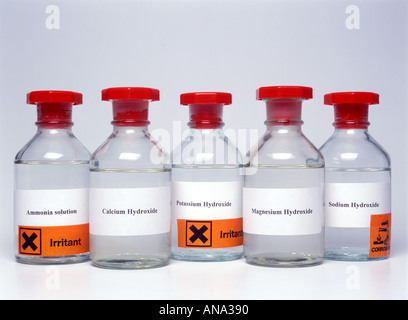 bottles of some soluble hydroxides with hazard labels against a white background Stock Photo