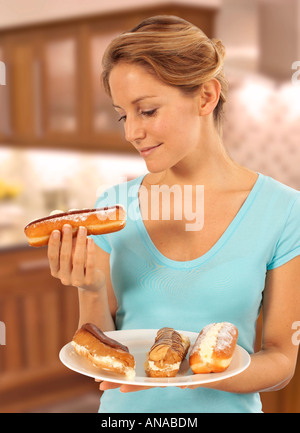 WOMAN EATING CREAM CAKES AND CREAM DOUGHNUTS Stock Photo