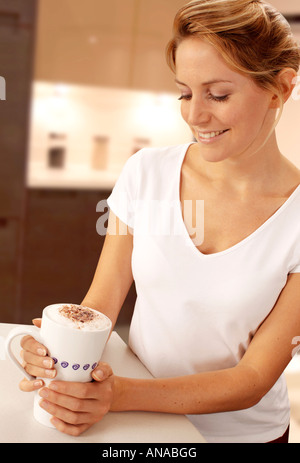WOMAN IN KITCHEN DRINKING CAPPUCCINO / LATTE COFFEE Stock Photo