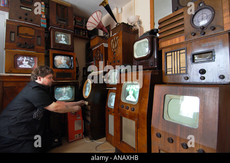 Old television collector Peter Carlton tunes one of his 14 vintage tvs to a video of the coronation of Queen Elizabeth 11 Stock Photo