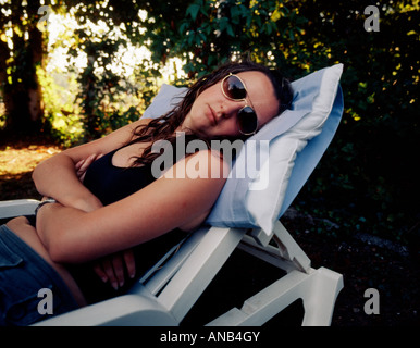 Young teenage woman 18 years old asleep in a lounger chair in the shade on a sunny day Stock Photo