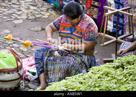 GUATEMALA ANTIGUA Cakchiquel Mayan woman wearing traditional huipil and corte using a backstrap loom to weave textiles Stock Photo