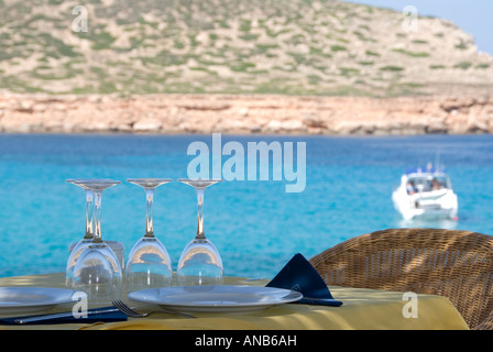 Restaurant on the beach overlooking the turquoise sea with a yacht in the background at Platges de Comte, Ibiza Stock Photo