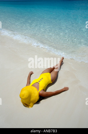 Turks and Caicos Provo woman lies in surf yellow hat and yellow bathing suit Stock Photo