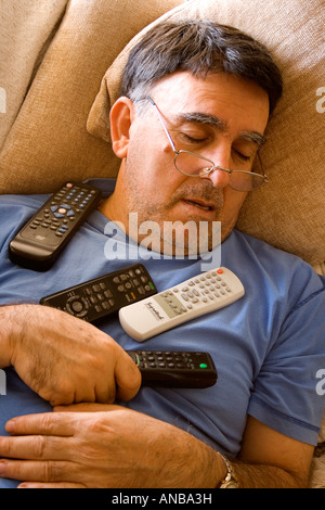 Man asleep with television remote controls Stock Photo