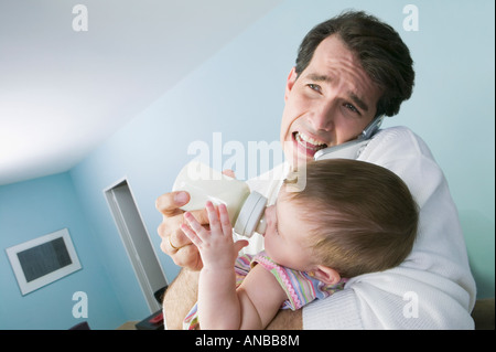 Stressed Hispanic father feeding baby Stock Photo