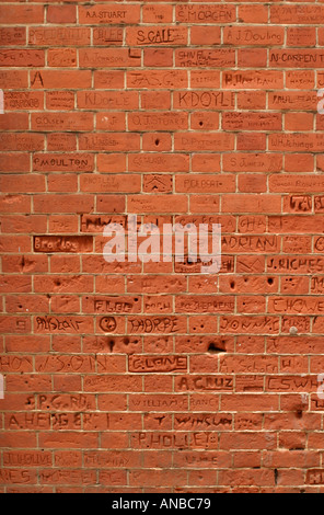 Names of schoolchildren scratched into red brick wall in school playground nr London UK Stock Photo