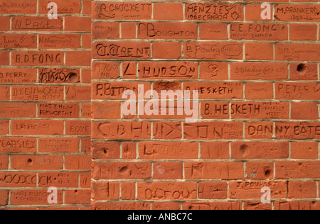 Names of schoolchildren scratched into red brick wall in playground nr London UK Stock Photo