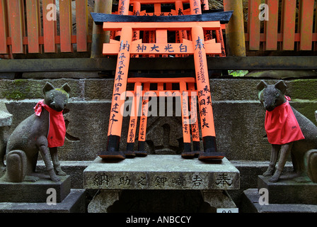 Stone sculptures of a fox with red bib Inari statue Fushimi Inari Taisha shrine in Kyoto Japan Stock Photo