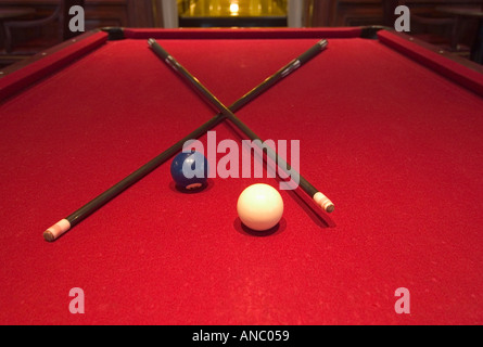 Red Pool Table with Sticks and Cue Balls Stock Photo