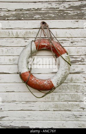 Old Red and White Life Preserver on Flaking White Wooden Panels Stock Photo