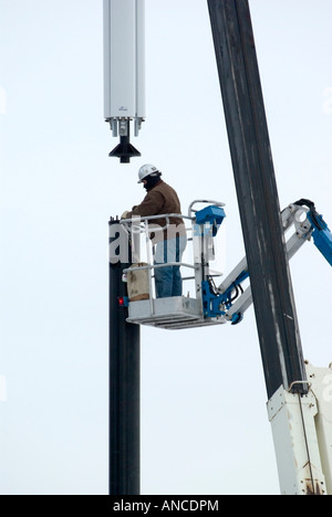 man installing cell phone antenna on tower Stock Photo