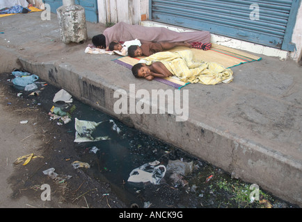 A homeless mother and her children sleeping on a pavement in India Stock Photo