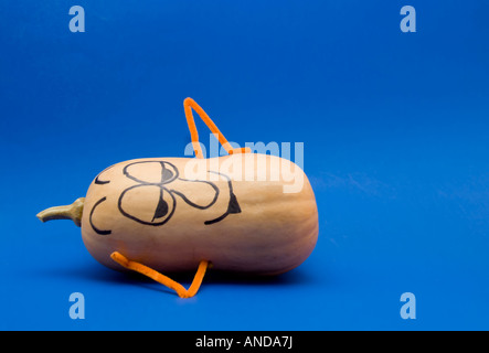 A butternut squash against a blue background used as a funny character with painted on face. Cutout. Stock Photo