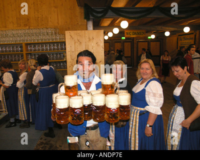 Waitress dressed in dirndl serving Liter glasses of beer in Oktoberfest Theresienwiese Munich Bavaria Germany Stock Photo