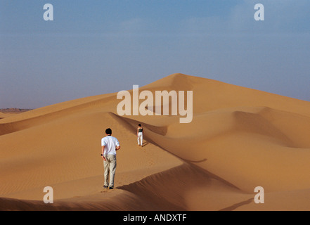 Tourists climbing a sand dune in the Sahara Desert Morocco Stock Photo