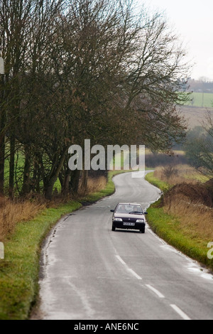 Car driving on a country road near Burford in the Cotswolds Oxfordshire United Kingdom Stock Photo
