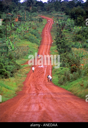 Rural tropic exotic hill palm banana tree mud road man go walk bike up down Moshi to Mount Kilimanjaro Tanzania East Africa Stock Photo