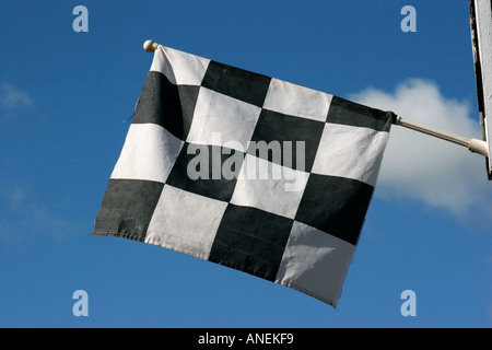 Chequered black and white flag against blue sky