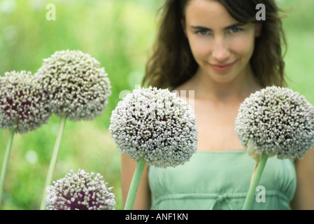 Woman looking at camera over allium flowers Stock Photo