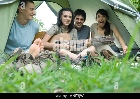 Friends in tent together, teen girl playing guitar Stock Photo