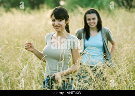 Young female hikers walking through field Stock Photo
