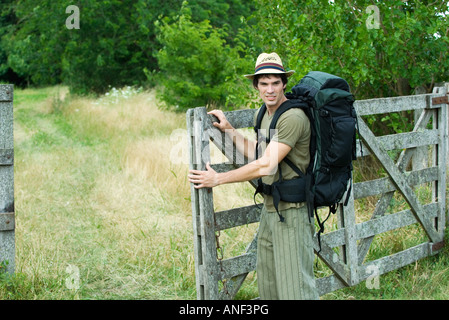 Hiker standing next to wooden gate Stock Photo