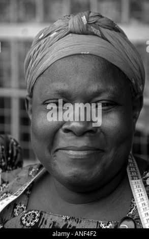 Smiling middle aged African Street tailor woman in traditional colourful clothing & hat Jinja City Uganda East Africa Stock Photo