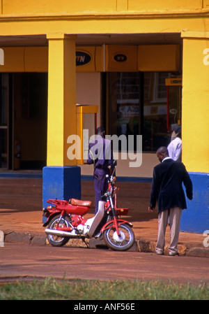 Street scene with detail of typical colonial architecture & colonnade & people man going about Jinja City Uganda East Africa Stock Photo