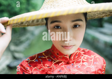 Young woman dressed in traditional Chinese clothing, holding edge of hat Stock Photo