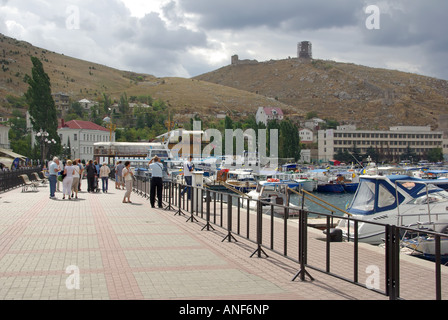 Balaclava bay harbour tourists and one time soviet nuclear submarine base boats beside promenade hillside Genoese fort beyond Stock Photo
