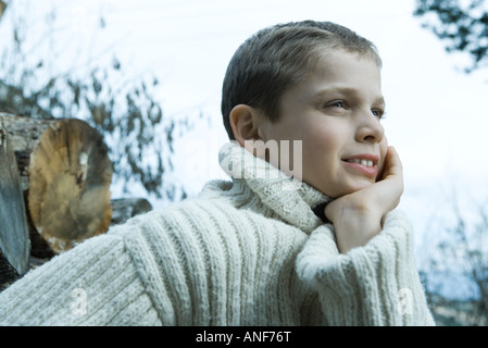 Boy wearing wool sweater, hand under chin, looking away Stock Photo