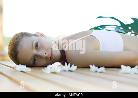 Woman lying on deck, surrounded by flowers Stock Photo
