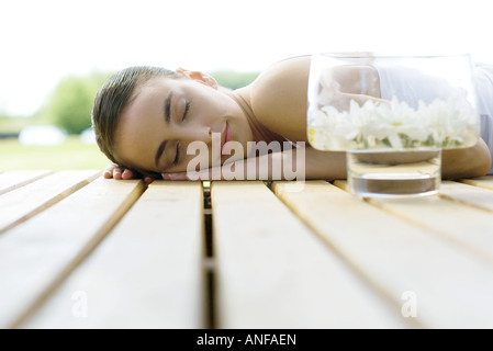 Woman lying on deck, next to container of floating flowers Stock Photo
