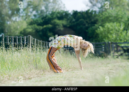 Young woman doing backbend in rural field Stock Photo