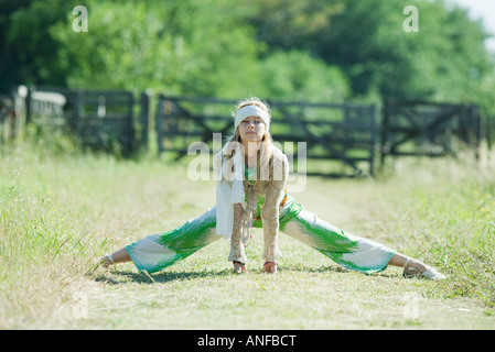 Young woman doing splits in rural field, smiling at camera Stock Photo