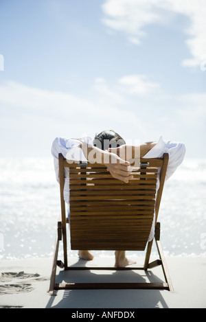Man sitting in deck chair, facing sea, rear view Stock Photo