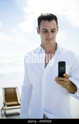 Young man using cell phone on beach Stock Photo